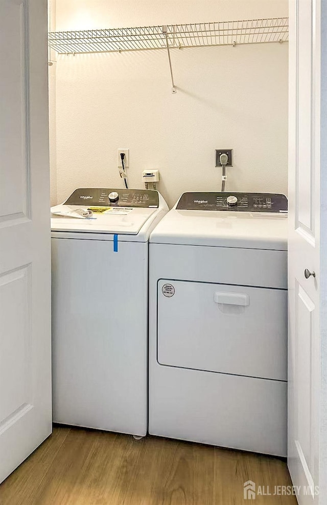 clothes washing area featuring laundry area, washer and dryer, and wood finished floors