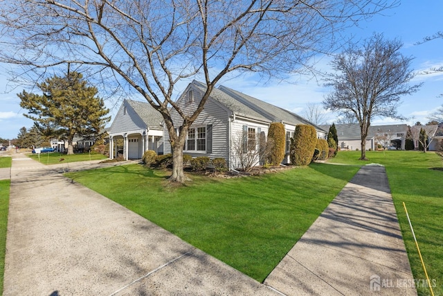 view of side of property with an attached garage, a lawn, and concrete driveway