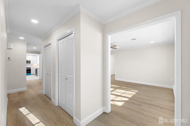 hall featuring light wood-style floors, baseboards, crown molding, and recessed lighting