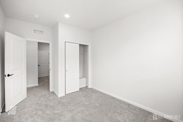 unfurnished bedroom with a closet and light carpet