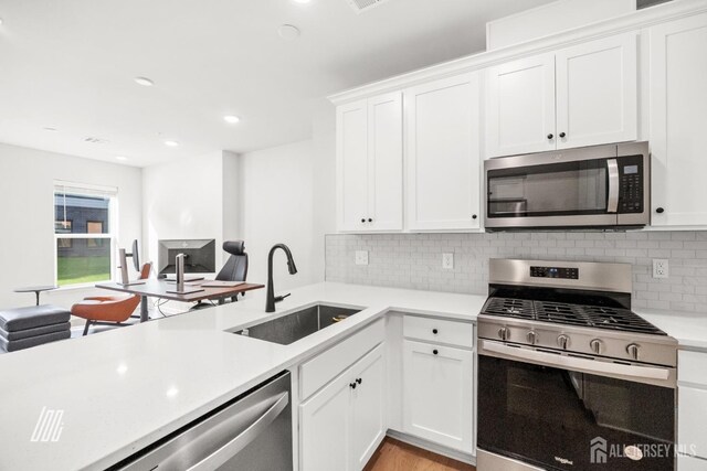 kitchen featuring stainless steel appliances, white cabinetry, tasteful backsplash, and sink