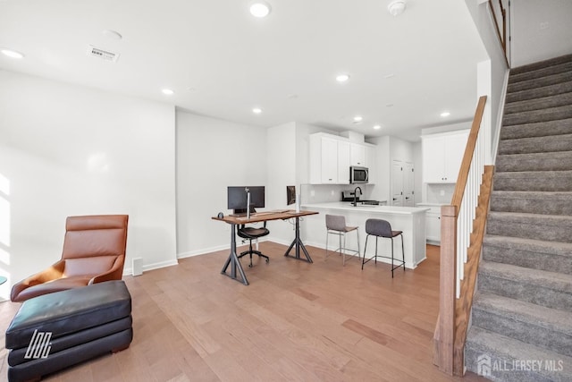 home office with sink and light hardwood / wood-style flooring