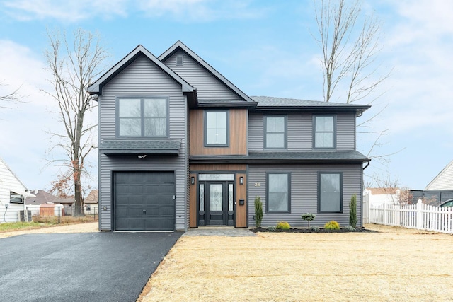 view of front facade featuring aphalt driveway, fence, and a garage