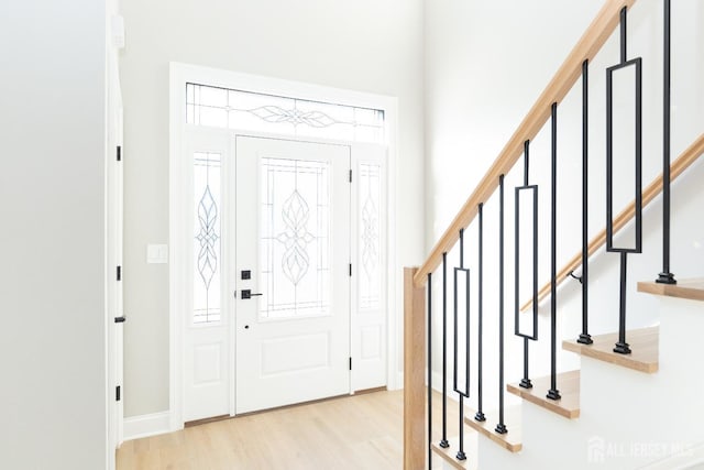 foyer with a healthy amount of sunlight, light wood-style flooring, a high ceiling, and stairs