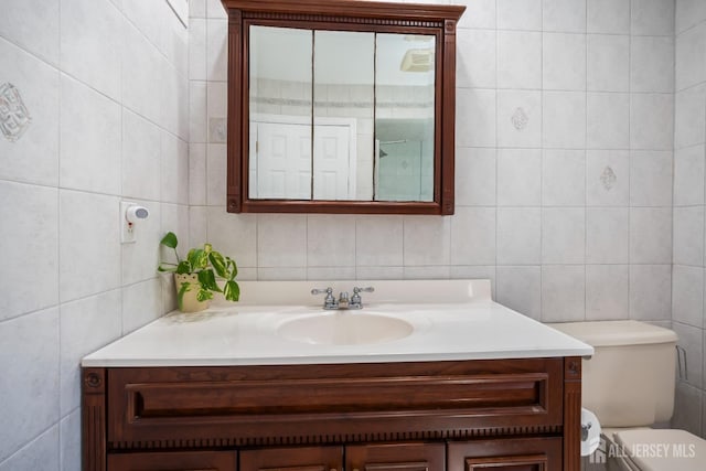 bathroom featuring tile walls, vanity, and toilet