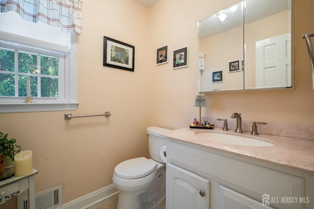 bathroom featuring toilet, vanity, and baseboards