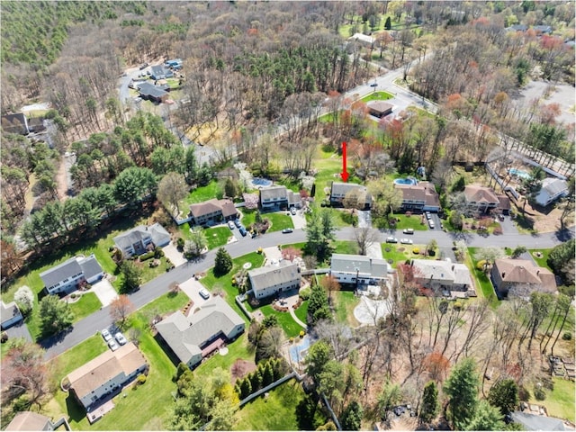 aerial view of property and surrounding area featuring nearby suburban area and a forest
