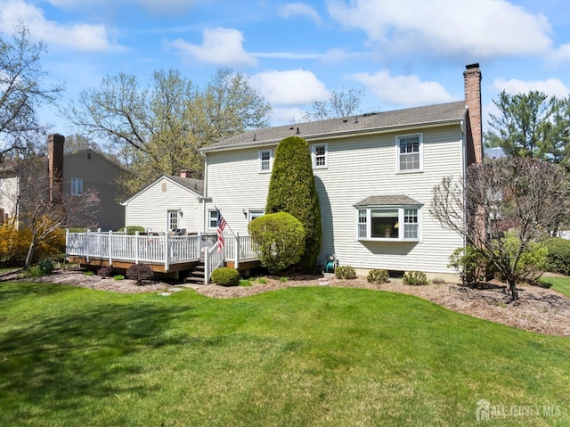 back of property featuring a chimney, a wooden deck, and a lawn