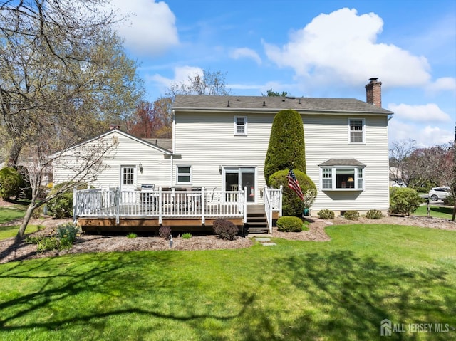 back of house featuring a chimney, a wooden deck, and a yard