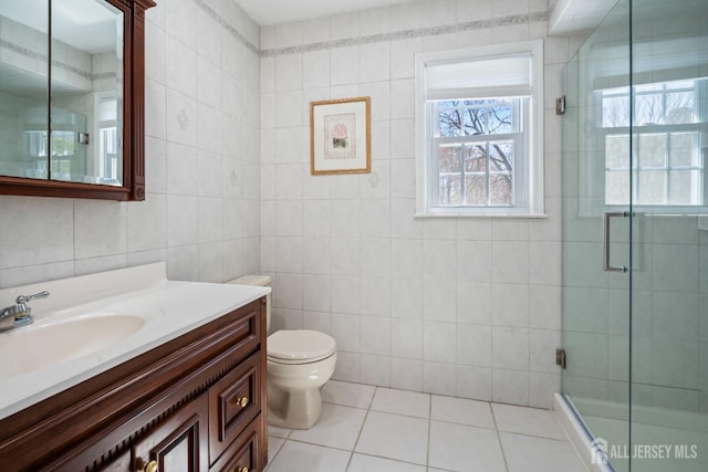 bathroom featuring tile walls, tile patterned floors, plenty of natural light, a shower with door, and vanity