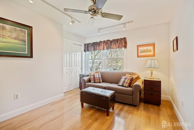 living area with track lighting, light wood finished floors, ceiling fan, and baseboards