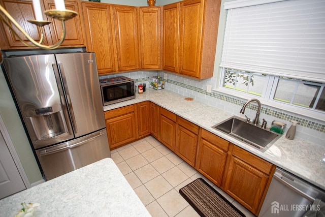 kitchen with light tile patterned floors, sink, backsplash, stainless steel appliances, and light stone counters