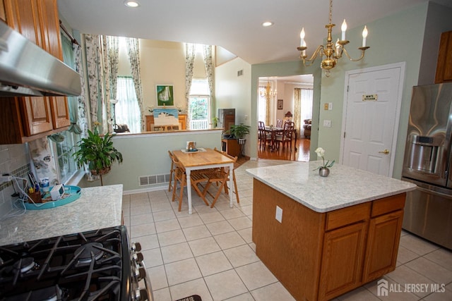 kitchen with a kitchen island, decorative light fixtures, stainless steel appliances, a chandelier, and range hood