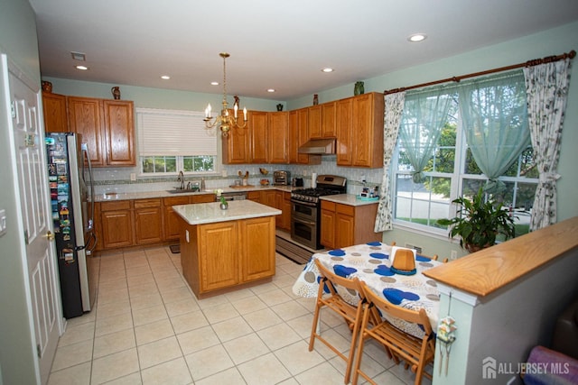 kitchen with a center island, a wealth of natural light, hanging light fixtures, and appliances with stainless steel finishes