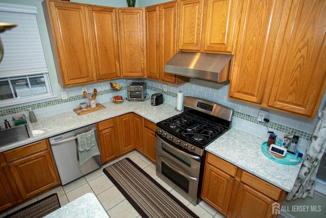 kitchen featuring decorative backsplash, light tile patterned floors, and appliances with stainless steel finishes