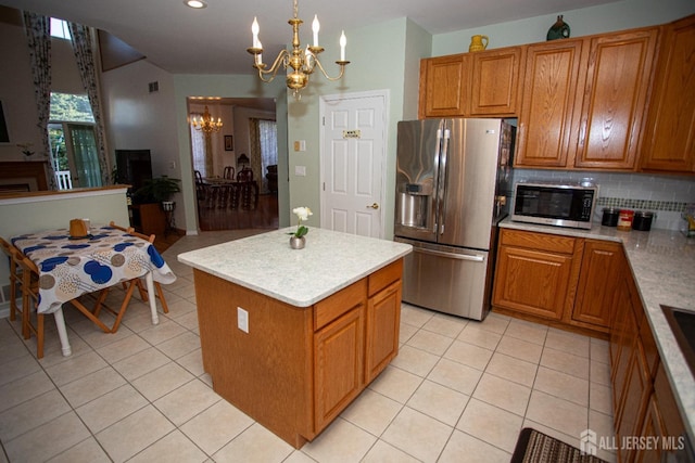 kitchen featuring pendant lighting, backsplash, a kitchen island, a chandelier, and stainless steel appliances