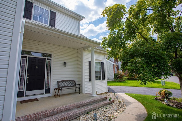 entrance to property featuring a porch and a yard