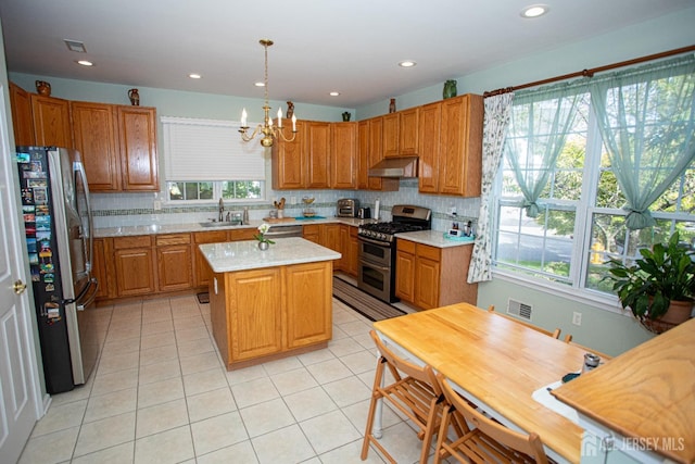 kitchen featuring a kitchen island, stainless steel appliances, an inviting chandelier, sink, and hanging light fixtures