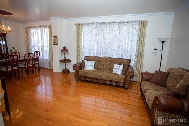 living room featuring wood-type flooring, a notable chandelier, and crown molding