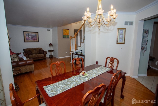 dining area with wood-type flooring, crown molding, and a chandelier