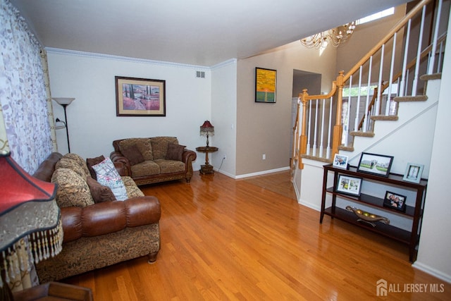 living room featuring hardwood / wood-style flooring, crown molding, and a notable chandelier