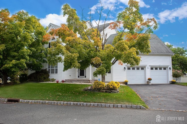 view of property hidden behind natural elements with a garage and a front lawn