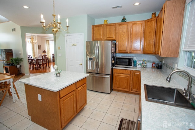 kitchen featuring tasteful backsplash, sink, hanging light fixtures, a kitchen island, and appliances with stainless steel finishes