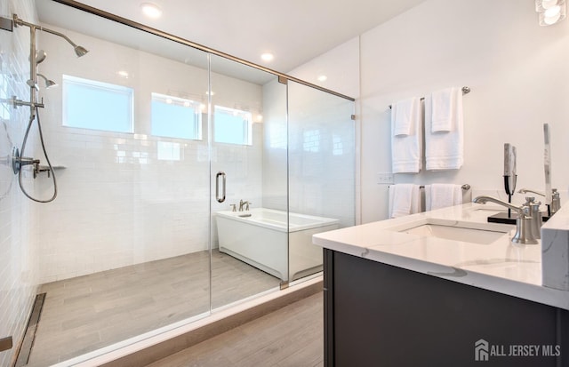 302 Nash Ave, West Windsor, NJ 08550 - full bathroom with double vanity, a stall shower, wood finished floors, a sink, and a tub to relax in