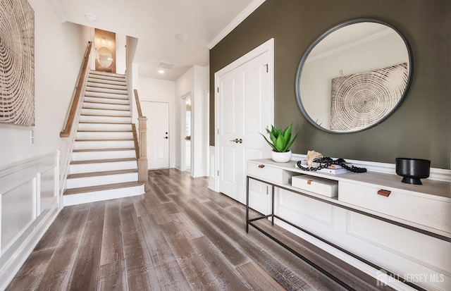 entryway featuring stairs, dark wood-type flooring, and ornamental molding