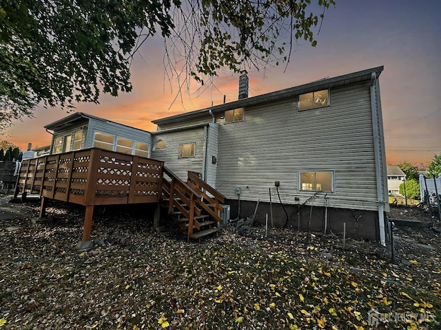 back house at dusk with a wooden deck