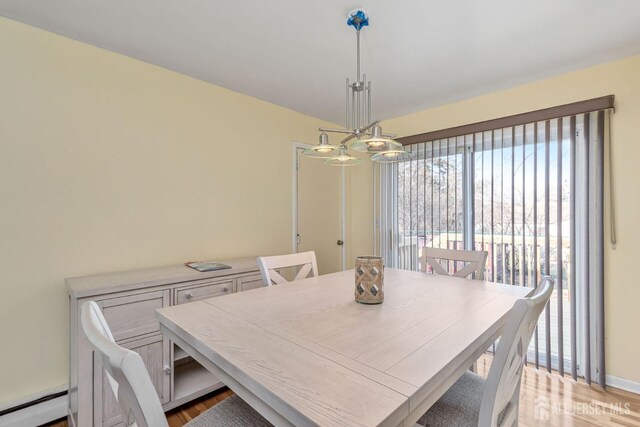 dining space featuring an inviting chandelier, baseboard heating, and light hardwood / wood-style floors