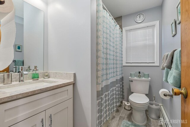 bathroom with vanity, toilet, wood-type flooring, and a baseboard heating unit