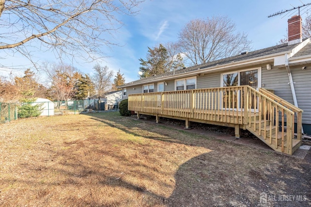 back of property featuring a deck and a lawn