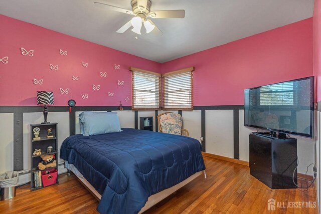 bedroom with wood-type flooring, a baseboard heating unit, and ceiling fan