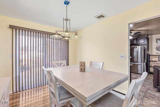 dining space with ceiling fan with notable chandelier and light hardwood / wood-style floors