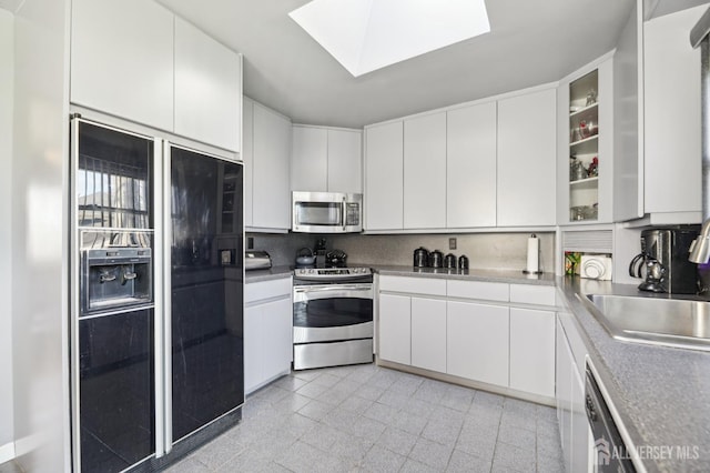 kitchen featuring glass insert cabinets, white cabinetry, appliances with stainless steel finishes, and a sink