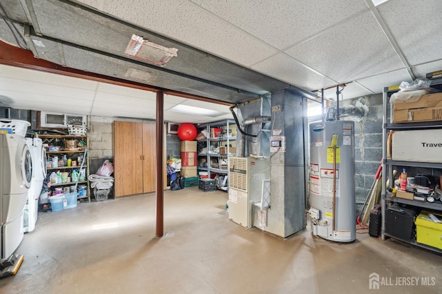 unfinished below grade area with heating unit, a paneled ceiling, washer and clothes dryer, and gas water heater