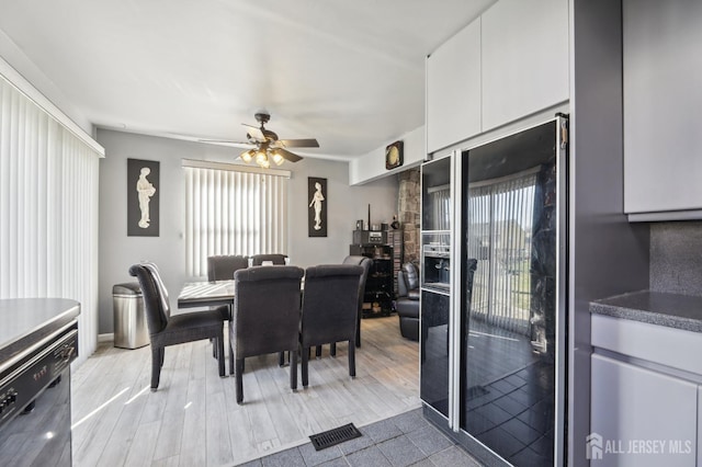 dining space with light wood-type flooring, visible vents, and ceiling fan