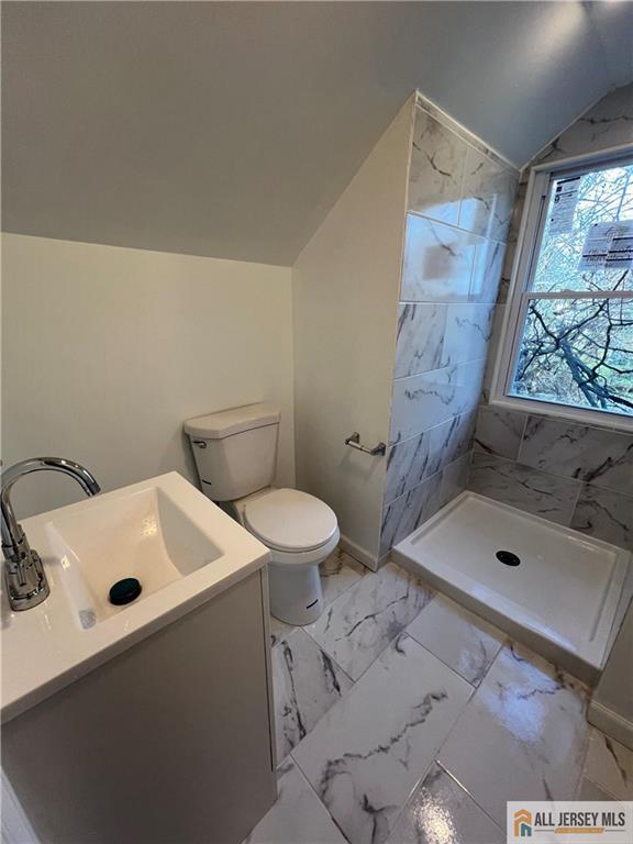 425 John St, Plainfield, NJ 07060 - bathroom featuring vanity, vaulted ceiling, toilet, tiled shower, and marble look tiles