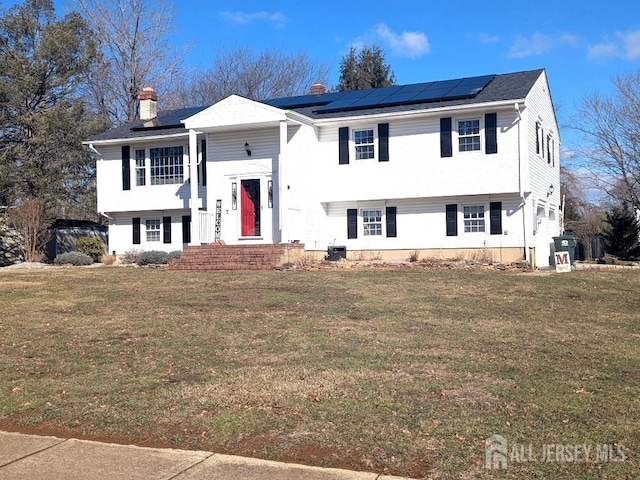 bi-level home featuring solar panels and a front yard