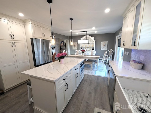 kitchen with a center island, white cabinetry, appliances with stainless steel finishes, and pendant lighting