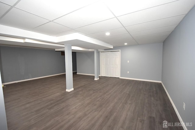 finished below grade area with dark wood-style floors, baseboards, and a paneled ceiling