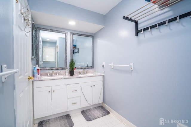 full bathroom with a sink, baseboards, double vanity, and tile patterned floors