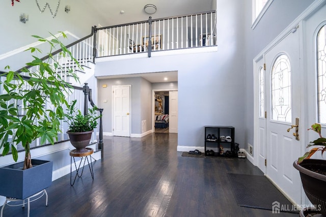 foyer featuring a towering ceiling, baseboards, wood finished floors, and stairs