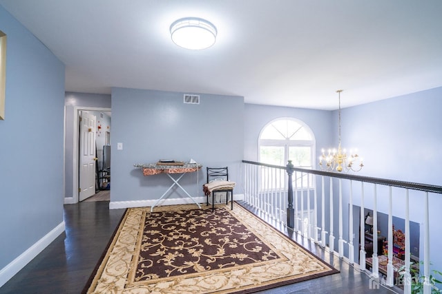 hall featuring a notable chandelier, visible vents, baseboards, and wood finished floors