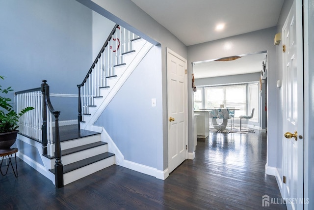 staircase featuring wood finished floors and baseboards