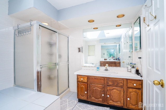 bathroom featuring tile patterned flooring, a shower stall, vanity, and a skylight