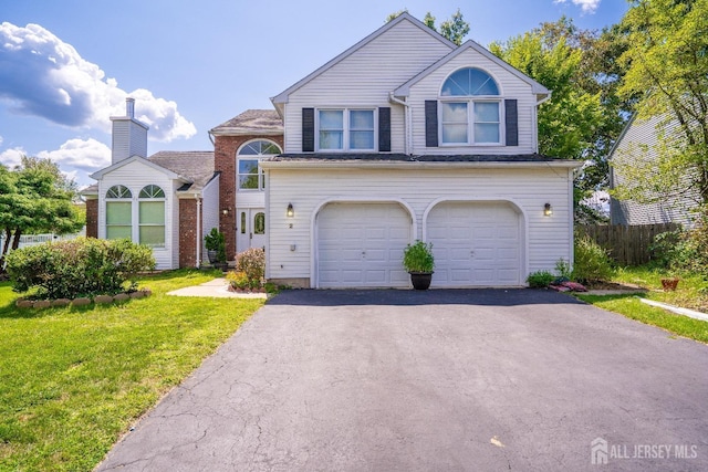 view of front of property with a front lawn, an attached garage, and driveway