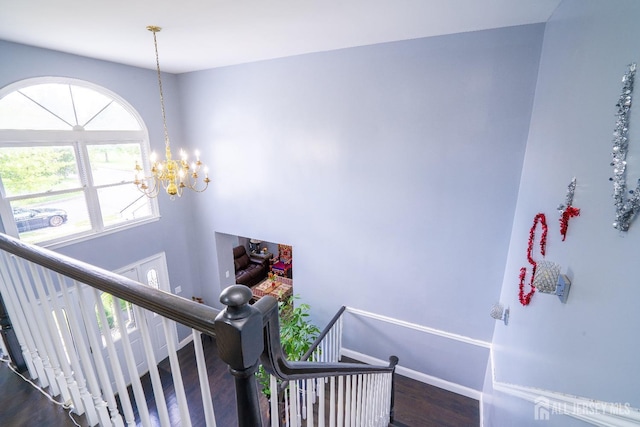 staircase featuring a chandelier, baseboards, and wood finished floors