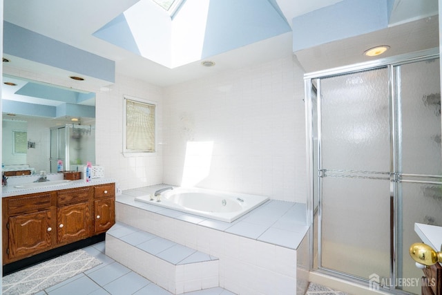 full bath featuring tile patterned floors, a garden tub, a skylight, a shower stall, and vanity